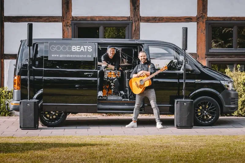 Die beiden Musiker des Konzert-Taxis am fertig aufgebauten Bulli mit Schlagzeug, Mischpult und Lautsprechern