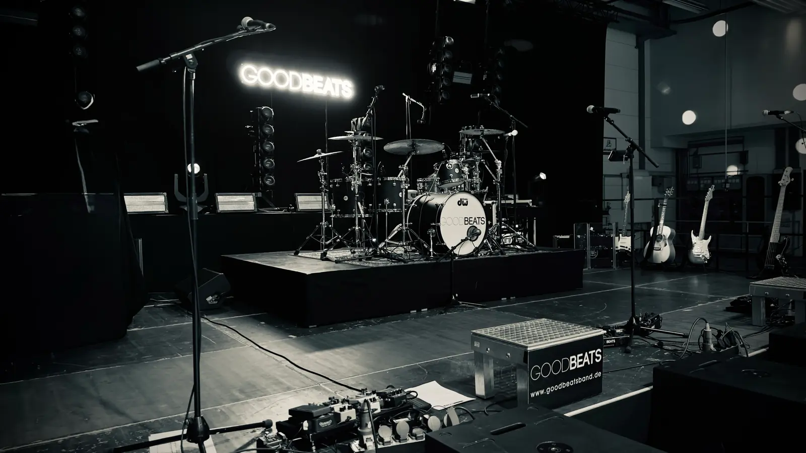 Liveband buchen: die Bühne der GOODBEATS vor der Show, Schlagzeug mit Bandlogo auf dem Podest, Mikrofone, Gitarren und die Leuchtschrift GOODBEATS