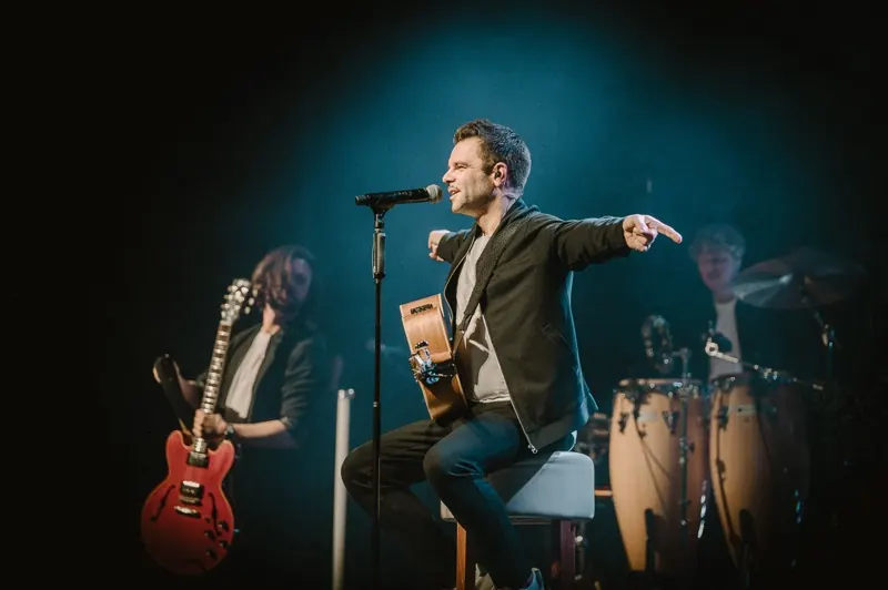 Winter Lounge: Der Sänger zeigt mit Akustikgitarre auf dem Schoß ins Publikum, dahinter Gitarre und Congas